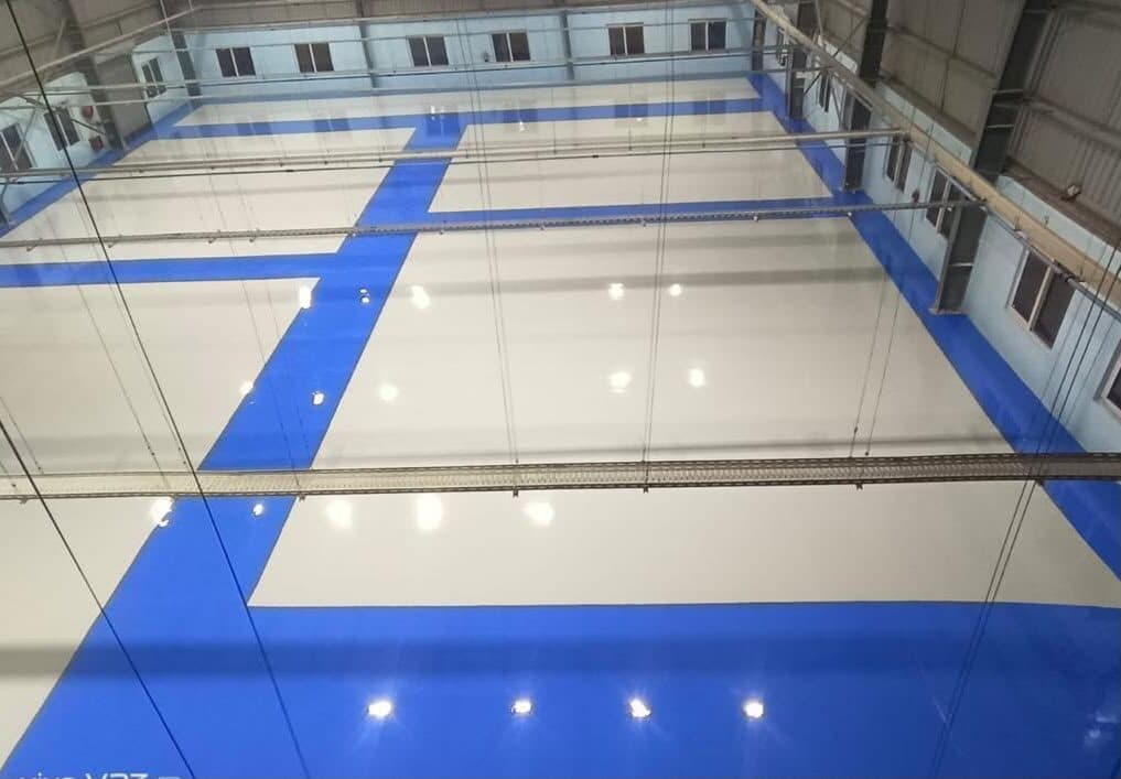 Glossy blue epoxy flooring inside an industrial warehouse